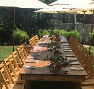 Outdoor setting with long family-style dinner table and umbrellas